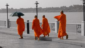 Buddhist Monks walking on the streets near the river in Thailand